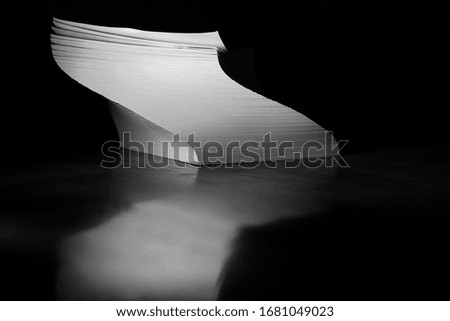 Pile of paper in a curved shape on a desk.