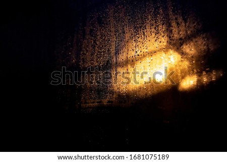 Rain drops on the glass on a background of a night blurred light