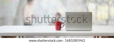 Cropped shot of portable workspace with laptop, coffee cup and copy space on white table with blurred background