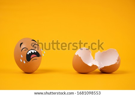 The egg has a sad expression. Crying with the farewell of another egg On a yellow background