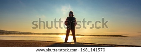 Athletic mature woman on the background of autumn sunrise on the sandy beach.