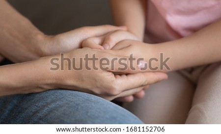 Crop close up of young mum holding little daughter hands having close tender intimate moment, mother and small girl child share secrets talking show love, care and affection, bonding, custody concept