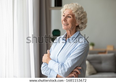 Happy elderly woman look in the window distance at home feel overjoyed excited about future, smiling mature female senior retired grandmother wait hope for the best to come, optimism concept Royalty-Free Stock Photo #1681153672