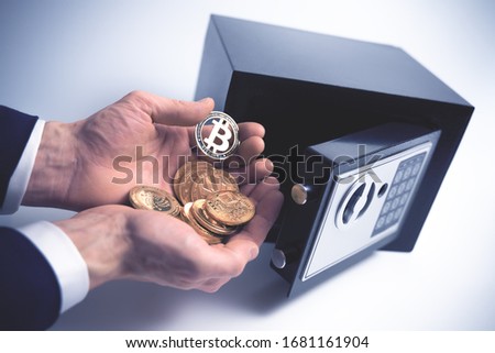 Safe Deposit. Symbol of cryptocurrency safety. The man puts a physical bitcoin in small Residential Vault. Toned soft focus picture.