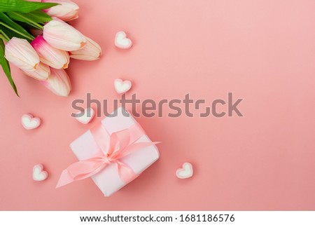 Top view aerial image of decoration Happy mother’s day holiday background concept.Flat lay white present box with flower on modern beautiful  pink paper at home office desk.Free space for design.