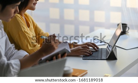 Photo of Website administrator/Customer supporter team working with computer tablet and sitting together at the long white working desk over modern office as background.