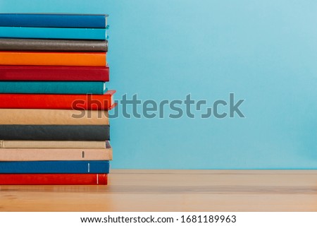 A simple composition of many hardback books, raw books on a wooden table and a bright blue background. back to school. Education.