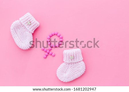 Pink booties for girl - pregnancy concept with Venus sign - on pink background top-down copy space