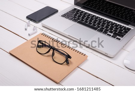 Smartphones and laptops on white wooden desks