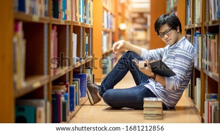Smart Asian man university student wearing glasses reading book by vintage bookshelf. Textbook resources in college library for educational subject and research. Scholarship for education opportunity. Royalty-Free Stock Photo #1681212856