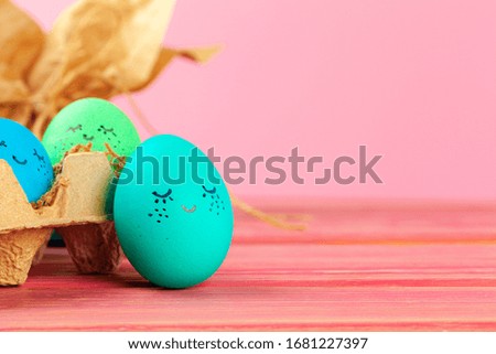 Blue and green colored Easter eggs with drawn funny faces. Creative photo