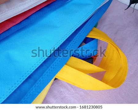 Amazing Colorful Eco Shopping Bags with green plant leaves and branches. Non woven bags on table. Use me i am bio bags