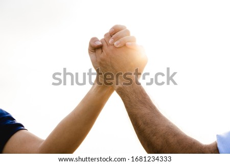 Closeup of two holding Hands on the sky background. Friendship, Helping Concept. Friendship Day.
