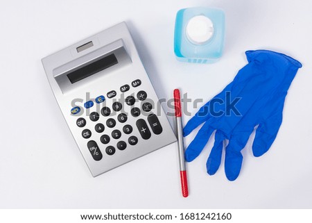 Desinfecting material, a red pen and a calculator on a white surface with copy space as a symbol of the economic effect of coronavirus crisis
