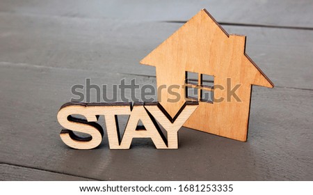 The wooden little house on the wooden desk and word "stay" near it. Stay home to stop spreading the virus reduce risk of infection. Protect world from Coronavirus