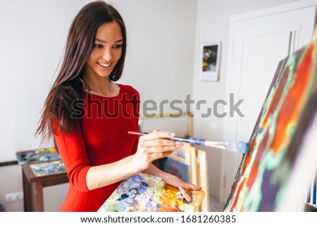 positive young artist girl paints a picture