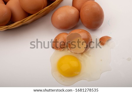 A broken chicken egg, chicken eggs in a wicker basket and eggs scattered on a white background. Close up.