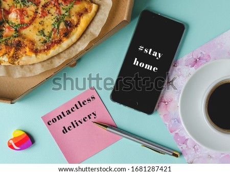 contactless delivery concept. Pizza in a box, a cup of coffee, a phone with the inscription #stay home and a sheet of paper with the inscription contactless delivery. 