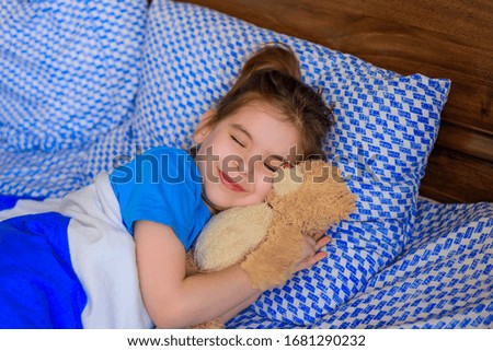 child little girl sleeps in the bed with a toy teddy bear