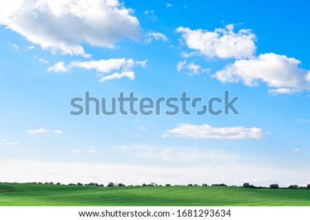 empty green grass field with blue sky and white clouds, natural screensaver on the monitor, beautiful landscape, sky and earth