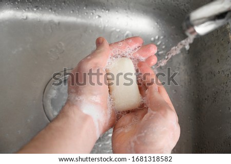Coronavirus infection protection. A man washes his hands with soap over a steel sink. Top view. Stop COVID-19 concept.