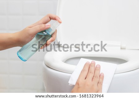 disinfect, sanitize, hygiene care. people using alcohol spray on toilet seat lid and frequently touched area for cleaning and disinfection, prevention of germs spreading during infections of COVID-19 Royalty-Free Stock Photo #1681323964