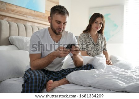 Young man preferring smartphone over spending time with his girlfriend at home. Jealousy in relationship Royalty-Free Stock Photo #1681334209