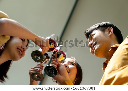 Bottome view - Three asian people toasting glasses of red wine.