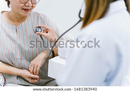 Young doctor using stethoscope to exam senior patient heart