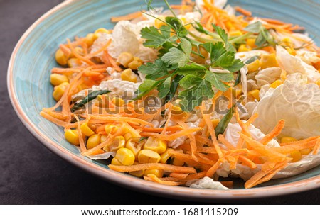 Vegetable salad with Chinese cabbage, carrots, corn, and parsley with green onions. Stock photo salad in a blue plate.