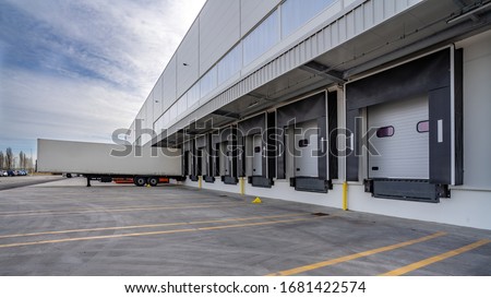 Row of loading docks warehouse building with truck. Royalty-Free Stock Photo #1681422574