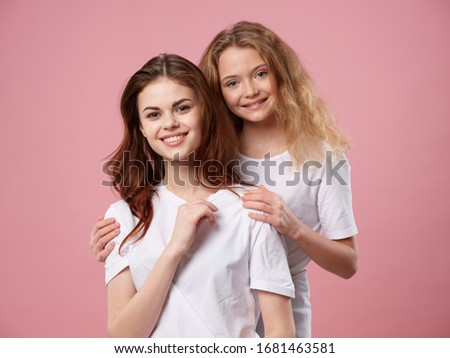 Mom and daughter hugs white t-shirts joy pink background fun