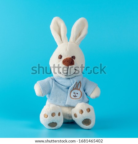 Cute bunny doll on blue background. Minimal Easter concept.
