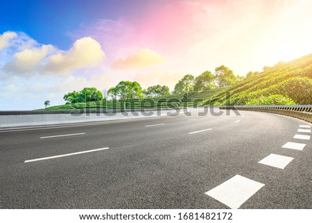 Empty asphalt road and green mountain nature landscape at sunset.