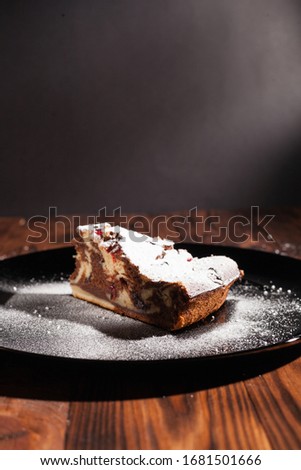 Rustic chocolate cake sprinkled with icing sugar. Chocolate cake on a wooden table.