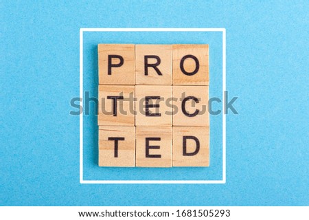 Word Protected arranged from wooden letters on blue background with white frame. Concept of safety and protection