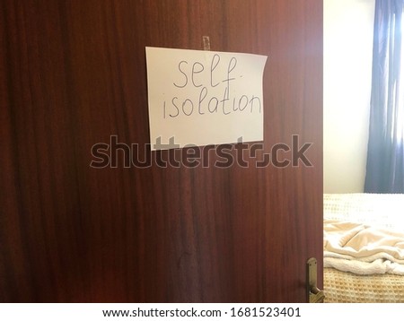 Wooden door with text sign Self-isolation on white paper across bedroom. Virus protection. Quarantine.