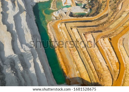 Top view on a stone quarry. Arial view on a mining of natural resources or ore. Green river separates white and yellow sand shores. Waterline with two types of a land. Natural texture.