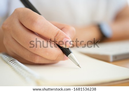 Close shot of businesswoman hands holding a pen writing something on the paper on the foreground in office. Recording concept Royalty-Free Stock Photo #1681536238