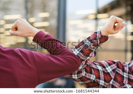 Two people bump elbows to avoid coronavirus outdoors. Friends demonstrating a new way of greeting during coronavirus epidemic. Health care concept. Social distancing. Royalty-Free Stock Photo #1681544344