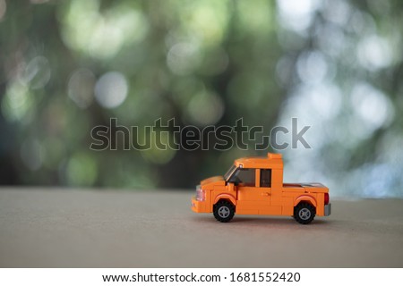 Miniature orange plastic toy car on wood table, pickup truck
