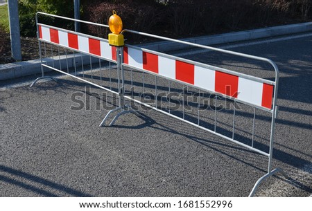 barrier against traffic entrance or traffic control portable with orange flashing reflector red-white stripes railing galvanized on the road side view