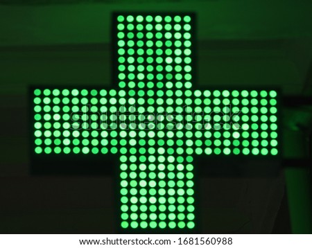 Photography of a green cross, the symbol used for medical intitutions. Symbol is located on the exterior of a building. Coronavirus Pandemic lifestyle of a city.