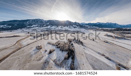 Aerial view of the small cozy german town at the mountain bottom at sunrise in a winter season, Halblech city, Germany, Bavaria, Branches of trees are covered with hoarfrost, sunny weather