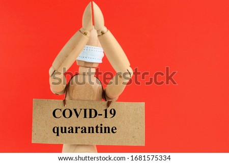 Cardboard sign with text covid-19 quarantine hanging on a wooden doll or mannequin in a medical mask. Concept of anti racism, the social distance, quarantine, situation around the Coronavirus Covid-19
