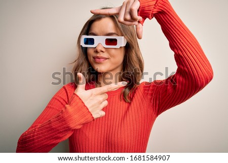 Young blonde girl wearing 3d cinema glasses over isolated background smiling making frame with hands and fingers with happy face. Creativity and photography concept.