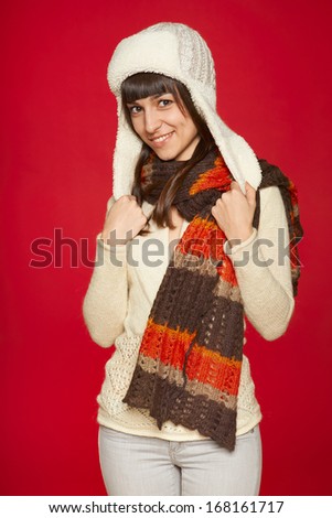 Christmas girl, young beautiful girl in hat and muffler smiling over red background