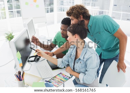 Side view of three artists working on computer at the office
