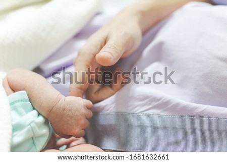 Newborn baby sleeping holding hands mom