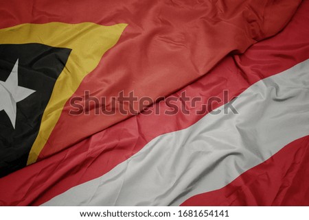 waving colorful flag of austria and national flag of east timor. macro